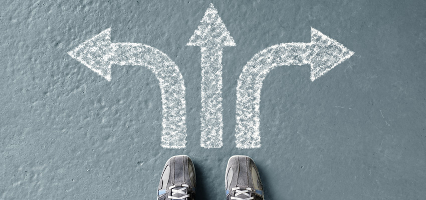 tennis shoes facing three arrows on the cement ground, one arrow to left, one to right and center arrow pointing forward.