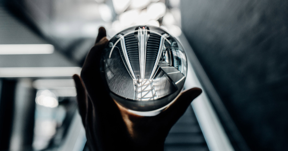 hand holds glass ball reflecting NY subway staircase