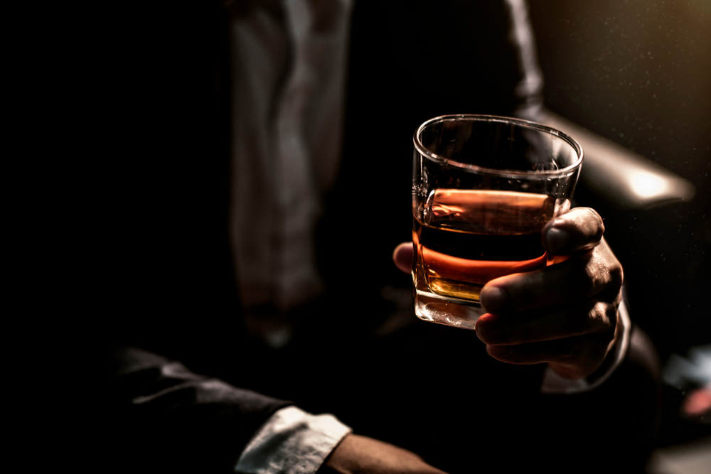 Businessman in dark room drinking glass of whiskey