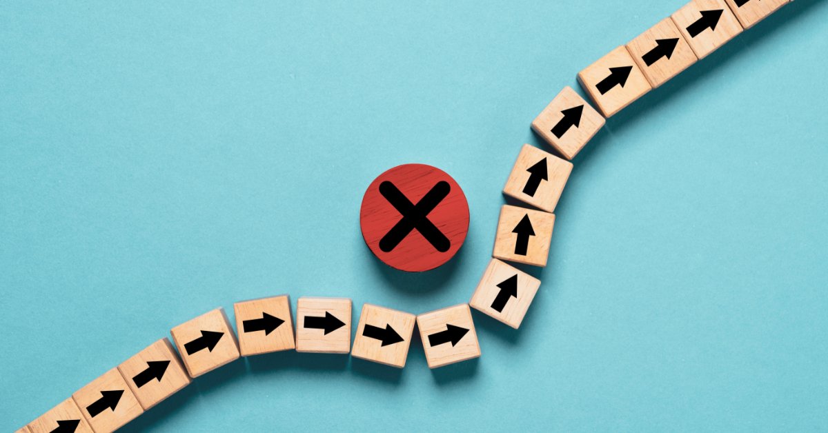 Wooden blocks marked with black arrows form a line that curves around a red wooden block marked with an X.